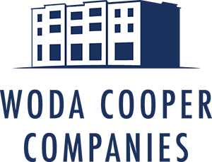 The image is a logo of Woda Cooper Companies featuring a building.